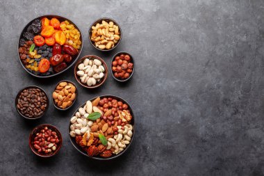 Koyu taş bir masada çeşitli kurutulmuş meyve ve fındıklar. Üst görünüm düzlüğü kopyalama alanı ile yatıyordu