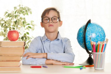 Genç okul çocuğu masada oturuyor ve ödev yapıyor. Temel eğitim konsepti