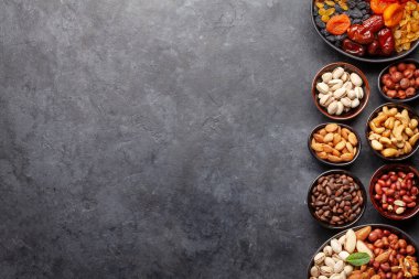 Koyu taş bir masada çeşitli kurutulmuş meyve ve fındıklar. Üst görünüm düzlüğü kopyalama alanı ile yatıyordu