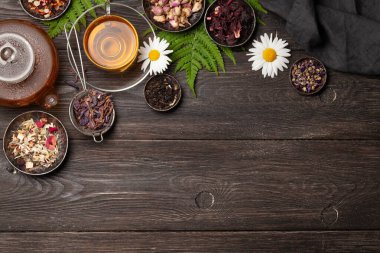 Çaydanlıkta çeşitli bitki çayları ve ahşap masada fincanlar. Kopyalama alanı olan üst görünüm. Düz yatıyordu