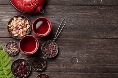 Çeşitli bitkisel çaylar, çaydanlık ve fincanlar ahşap masada. Kopyalama alanı olan üst görünüm. Düz yatıyordu