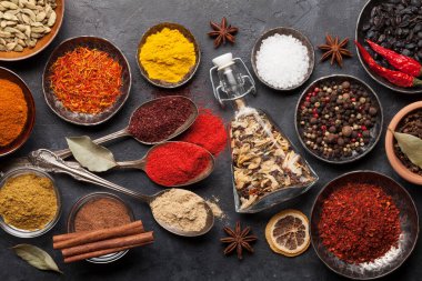 Koyu taş masada çeşitli baharatlar ve kaşıklar. Hint mutfağı. Üst görünüm düzlüğü
