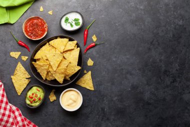Çeşitli soslu Meksika cipsi. Guacamole, salsa, peynir ve ekşi krema. Üst görünüm düz taş masa üzerinde kopya alanı ile yatıyordu