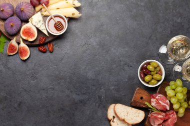 Prosciutto, peynir, incir ve üzümlü Antipasto tabağı. Aperatif panosu ve beyaz şarap. Üst görünüm düzlüğü kopyalama alanı ile yatıyordu
