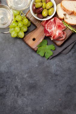 Prosciutto, zeytin ve üzümlü Antipasto tabağı. Aperatif panosu ve beyaz şarap. Üst görünüm düzlüğü kopyalama alanı ile yatıyordu
