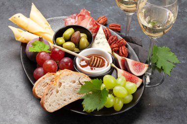 Prosciutto, peynir, incir ve üzümlü Antipasto tabağı. Aperatif panosu ve beyaz şarap.