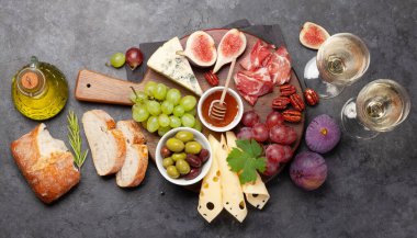 Prosciutto, peynir, incir ve üzümlü Antipasto tabağı. Aperatif panosu ve beyaz şarap. Üst görünüm düzlüğü