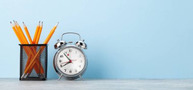 Ofis not defteri malzemeleri ya da okul kitapları ve alarm saati mavi duvarın önünde metnin için bir kopya alanı ile birlikte.