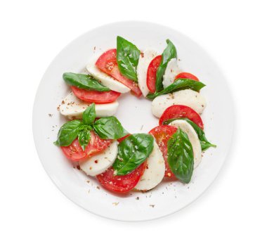 Caprese salatası. Mozzarella peyniri, domates ve fesleğen yaprağı. Üst görünüm düz beyaz üzerinde izole yatıyordu