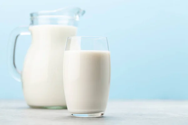 Milch Glas Und Krug Vor Blauem Hintergrund Mit Kopierraum — Stockfoto