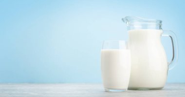Süt cam ve sürahi mavi arkaplan önünde kopyalama alanı ile