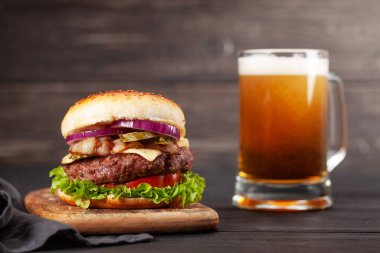 Büyük sığır eti, peynir, domates, pastırma, marul ve bira bardağıyla ev yapımı lezzetli hamburger. Kopyalama alanı ile