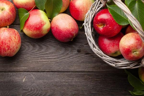 Olgun bahçe elması meyveleri sepetin içinde, tahta açık masa üzerinde fotokopi alanı ile birlikte. Üst görünüm düzlüğü