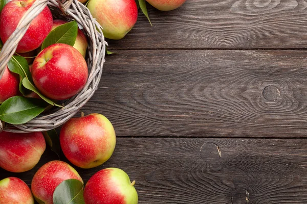 Olgun bahçe elması meyveleri sepetin içinde, tahta açık masa üzerinde fotokopi alanı ile birlikte. Üst görünüm düzlüğü