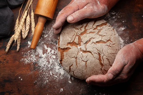 Baker Håller Nybakat Hembakat Bröd Händerna Träbord Ovanifrån Platt Låg — Stockfoto