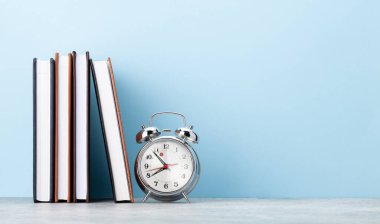 Ofis not defteri malzemeleri ya da okul kitapları ve alarm saati mavi duvarın önünde metnin için bir kopya alanı ile birlikte.