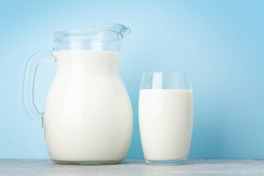 Süt cam ve sürahi mavi arkaplan önünde kopyalama alanı ile