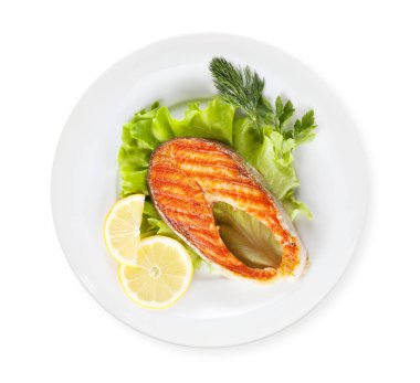 Limonlu ızgara somon bifteği ve salata. Üst görünüm düz beyaz üzerinde izole yatıyordu