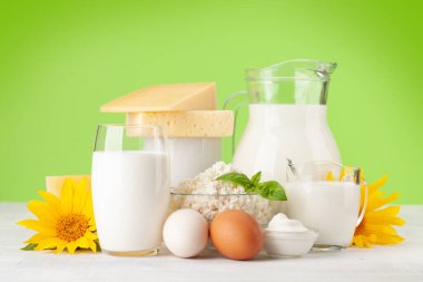 Çeşitli süt ürünleri. Süt, peynir, kulübe, ekşi krema. Yeşil arkaplanın önünde
