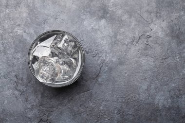 Taş masanın üzerinde buz küpleri olan bir bardak su. Üst görünüm düzlüğü kopyalama alanı ile yatıyordu