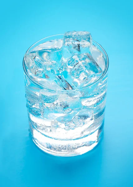蓝色底座上装有冰块的杯子水 — 图库照片