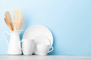 Mutfak gereçleri ve tabaklar mavi arkaplan önünde fotokopi alanı ile