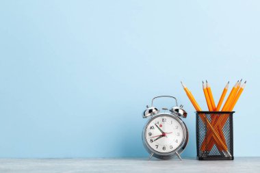 Ofis not defteri malzemeleri ya da okul kitapları ve alarm saati mavi duvarın önünde metnin için bir kopya alanı ile birlikte.