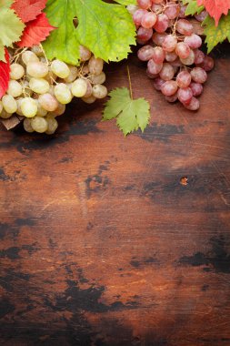 Üzüm ve sonbahar yaprakları ahşap masada. Üst görünüm düzlüğü kopyalama alanı ile yatıyordu
