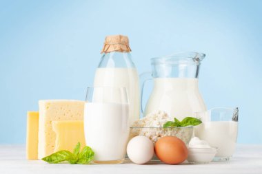 Çeşitli süt ürünleri. Süt, peynir, kulübe, ekşi krema. Mavi arkaplanın önünde