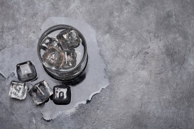 Taş masanın üzerinde buz küpleri olan bir bardak su. Üst görünüm düzlüğü kopyalama alanı ile yatıyordu