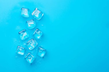 Buz küpleri ve su damlaları mavi arkaplanda. Üst görünüm düzlüğü kopyalama alanı ile yatıyordu