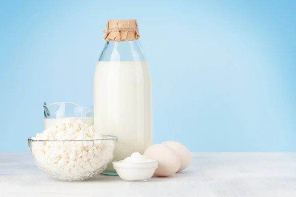 Various dairy products. Milk, cottage, sour cream and eggs. In front of blue background with copy space