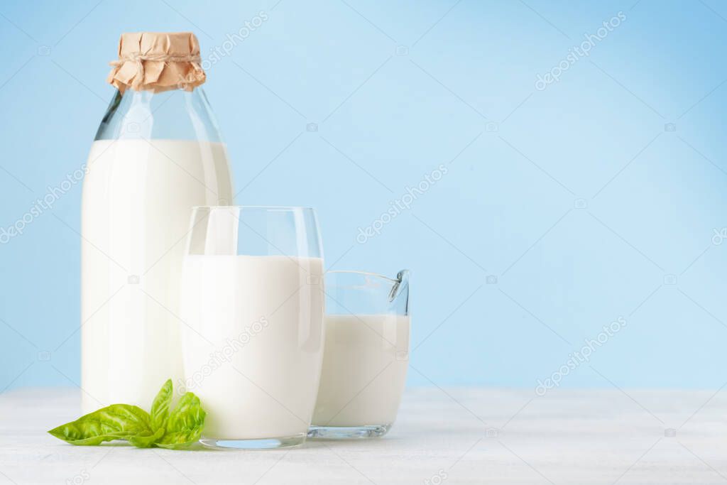 Milk in bottle, jug and glass. In front of blue background. With copy space