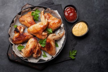 Soslu ızgara tavuk kanadı. Taş masadaki üst görünüm