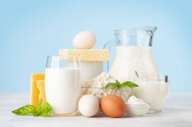 Çeşitli süt ürünleri. Süt, peynir, kulübe, ekşi krema. Mavi arkaplanın önünde