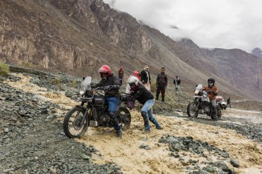 Nubra Vadisi, Hindistan - 29 Haziran 2017: nehir erime üzerinden akan geçmeye bisikletçileri yardım kar Himalaya dağlarında, Ladakh bölge, Hindistan