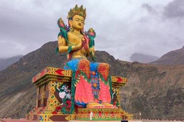Maitreya Buddha statue with Himalaya mountains in back at Diskit Monastery, Nubra Valley, Ladakh, India. clipart