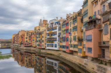 Sarı, kırmızı ve turuncu renkli evleri su Nehri Onyar, Girona, Catalonia, İspanya yansıması Katalan bayraklı.