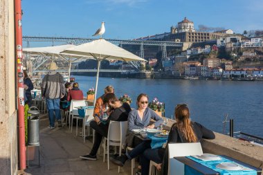 Porto, Portekiz - 19th Ocak 2018: Ponte dom güzel bir manzaraya ile nehir Douro kıyısında açık kafede öğle yemeği insanlar Luis köprü Porto, Portekiz