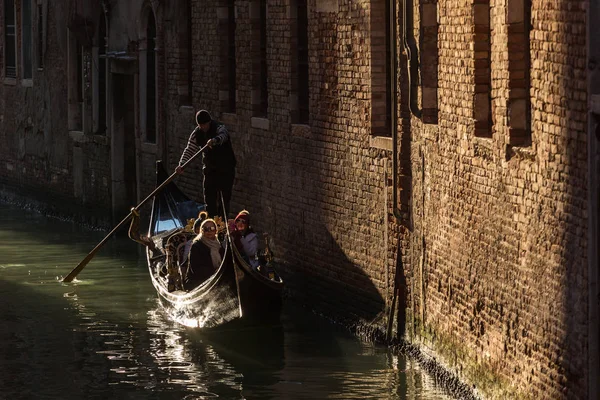 Venetsialainen gondolier ratsastus turisteja gondoli läpi puolella kapea kanava Venetsiassa . — kuvapankkivalokuva