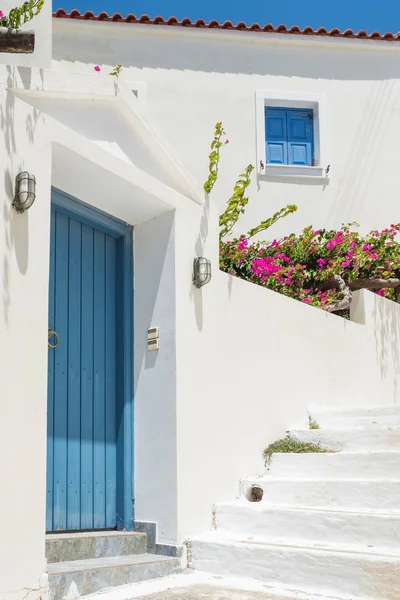 Fachada da casa branca com porta azul tradicional e flores na ilha Andros, Cíclades — Fotografia de Stock