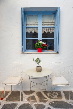 Beyaz Saray cephesi mavi pencere, masa ve sandalyeler Naoussa kasabası, Paros adası, Cyclades