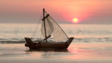 Gün batımında kum sahilde küçük tekne oyuncak