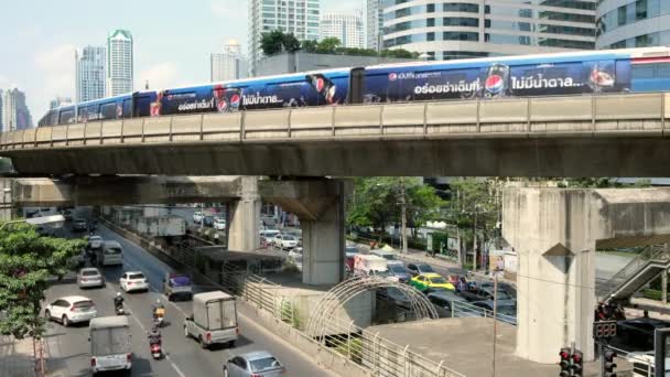 Bts skytrain fährt über die vielbefahrene straße in bangkok, thailand — Stockvideo