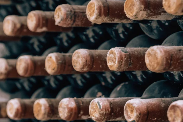 Μπουκάλια κρασιού στοιβαγμένα σε παλιό κελάρι κοντά-up φόντο — Φωτογραφία Αρχείου