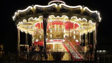 Geceleyin bir lunaparkta aydınlatılmış klasik çocuk atlıkarıncaları.