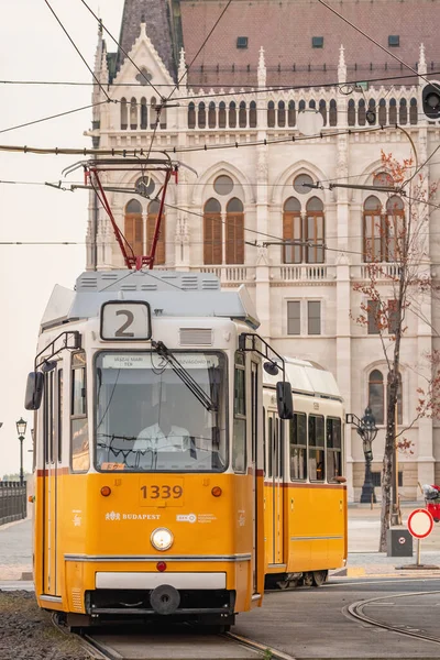 Старый желтый трамвай перед зданием венгерского парламента в Будапеште — стоковое фото