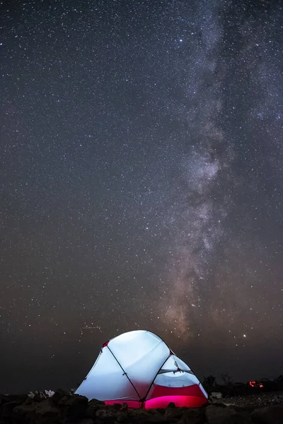 Uma tenda brilha sob um céu noturno cheio de estrelas . — Fotografia de Stock