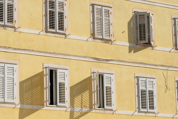 Traditionelles Gebäude im mediterranen Stil mit weißen Fensterläden an gelber Wand — Stockfoto