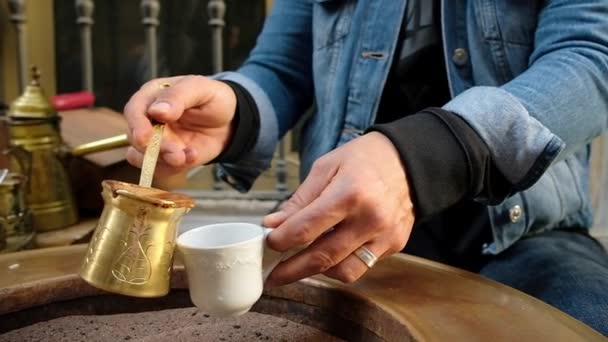 Vrouwen handen gieten traditionele Turkse koffie in een kopje. — Stockvideo